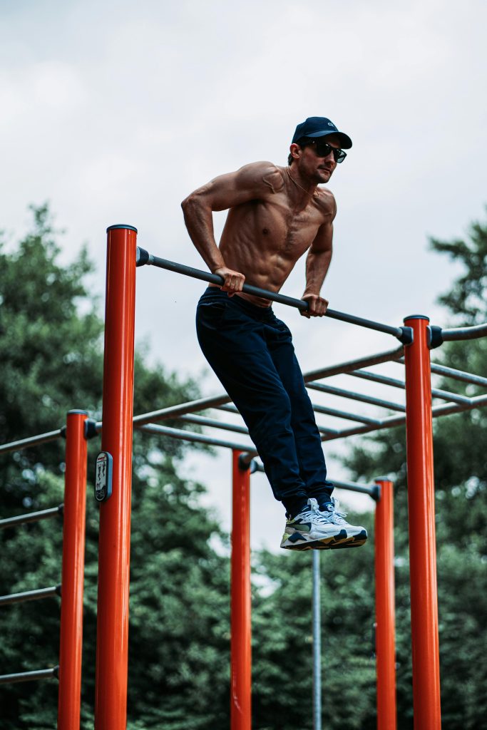 Fit man doing a workout on outdoor pull-up bars, showcasing strength and fitness.